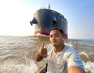 Jovem do AP desafia o perigo e viraliza ao navegar de rabeta com navio gigante