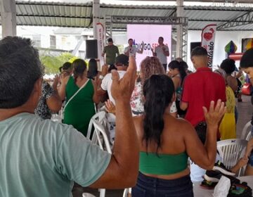 Famílias carentes agradecem orando ao receber alimentos