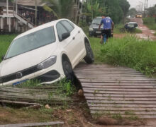 Motorista tenta encurtar caminho por ponte de madeira e carro acaba em canal